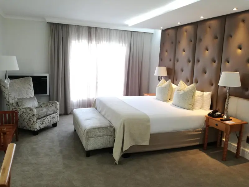 Une chambre lumineuse avec un grand lit et un fauteuil.