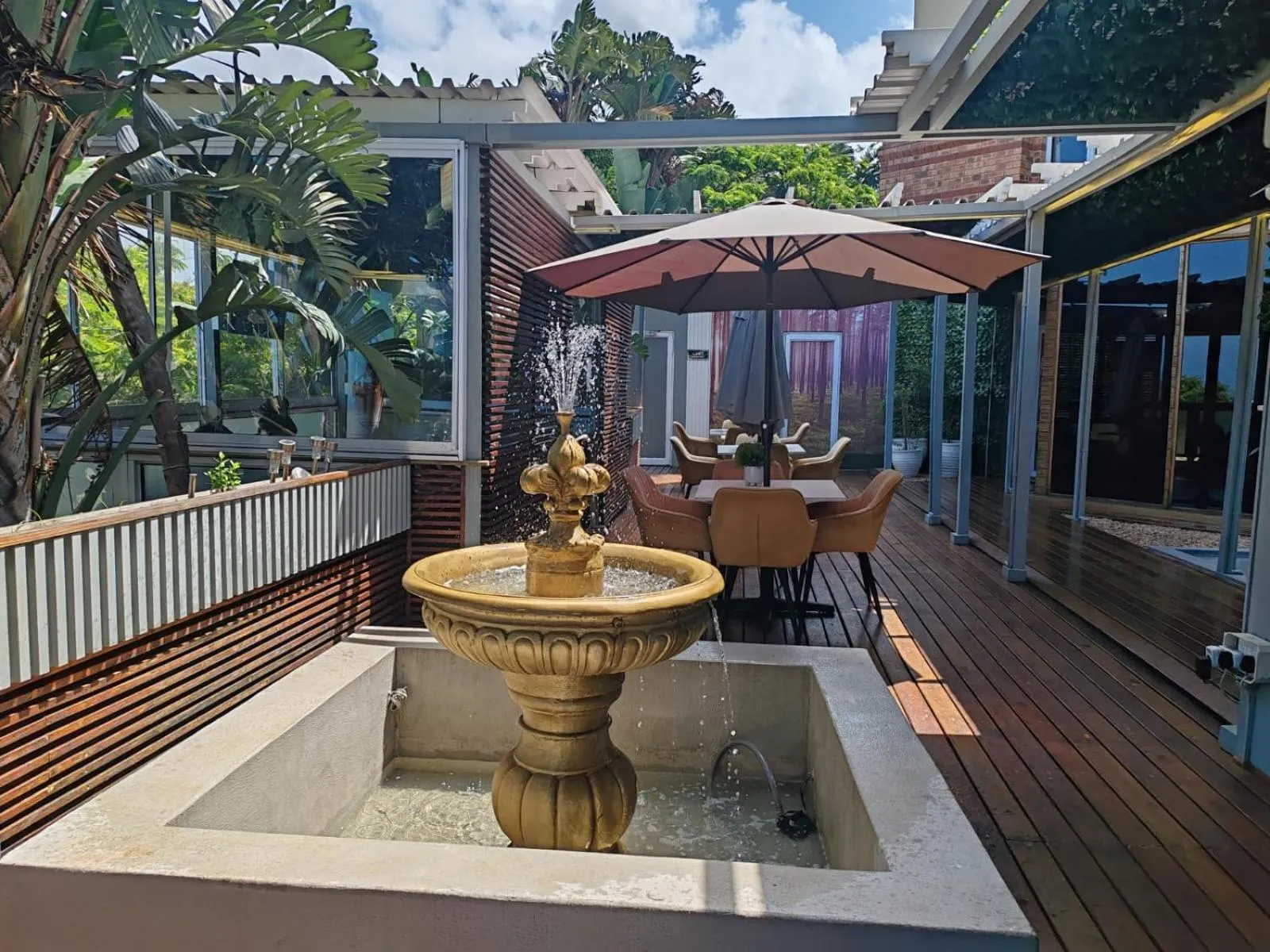 Terrasse ombragée avec fontaine et mobilier de jardin.