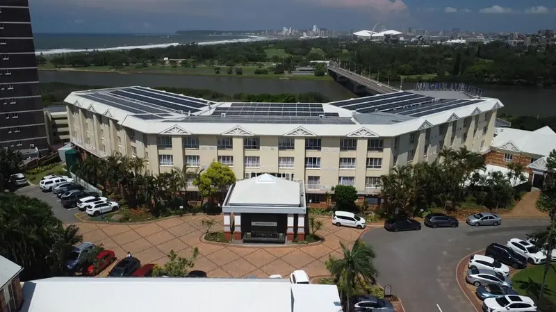 Vue aérienne d'un bâtiment blanc avec des panneaux solaires et un parking.