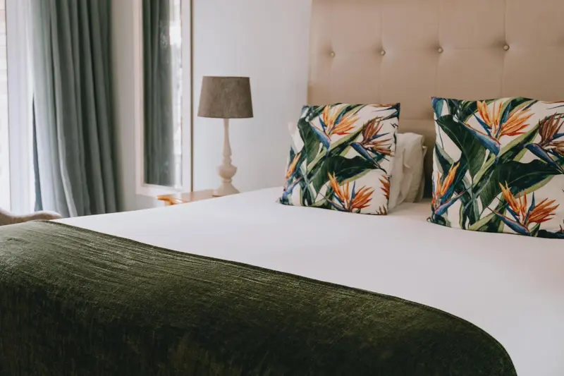 Un lit double avec une couverture verte et des oreillers décorés de motifs floraux.