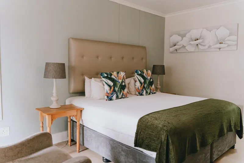 Une chambre lumineuse avec un grand lit recouvert d'une couverture verte.