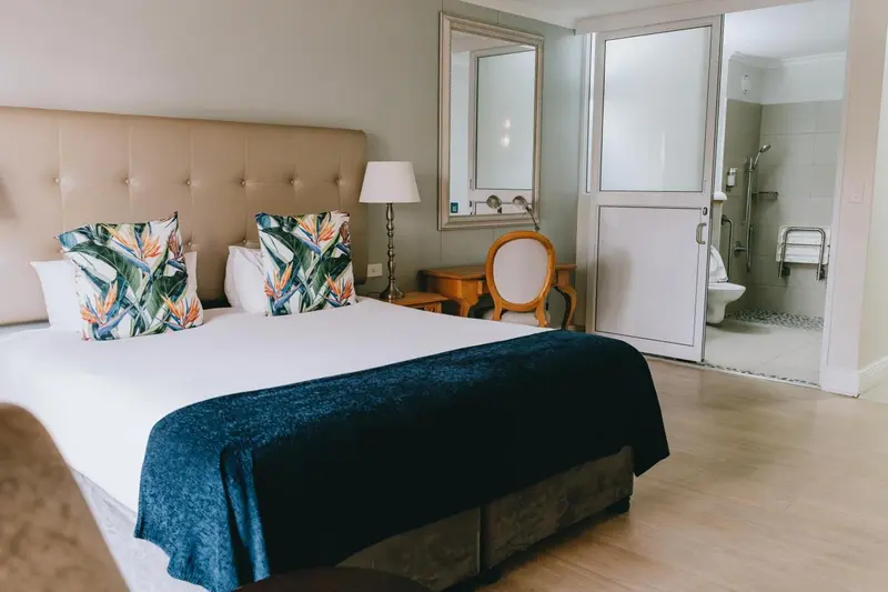 Une chambre lumineuse avec un grand lit et un coin toilette.