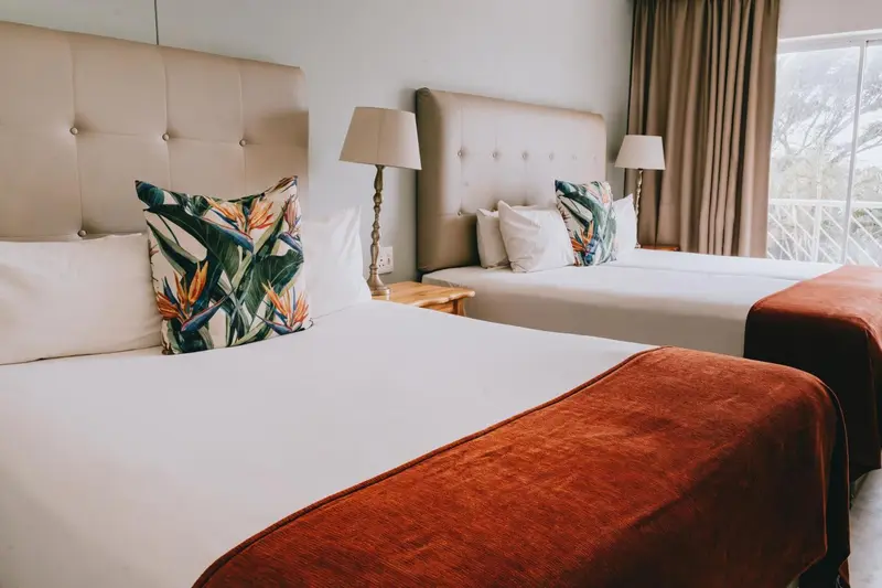 Deux lits simples avec des oreillers et des couvertures dans une chambre d'hôtel.