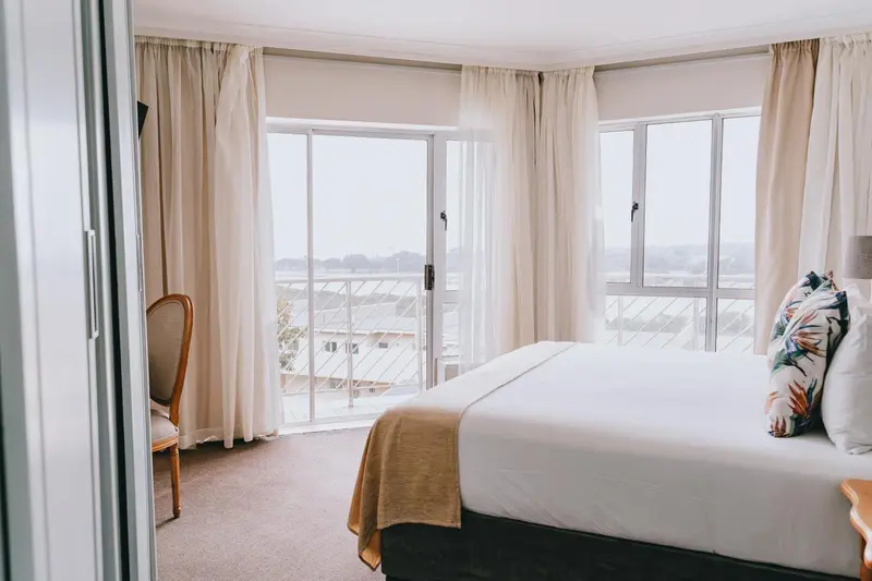 Chambre lumineuse avec un grand lit et vue sur le paysage.