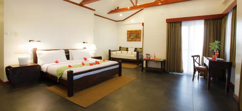 Une chambre lumineuse avec un lit double décoré et un coin salon.