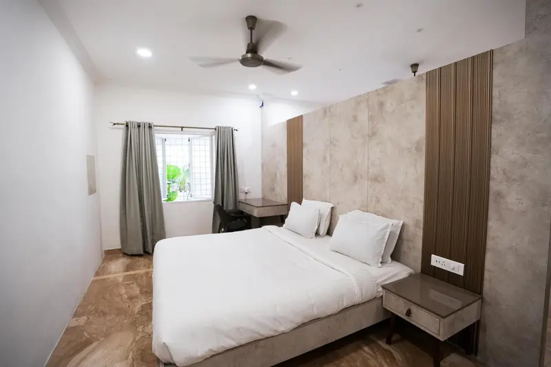 Une chambre lumineuse avec un lit double et un bureau près de la fenêtre.
