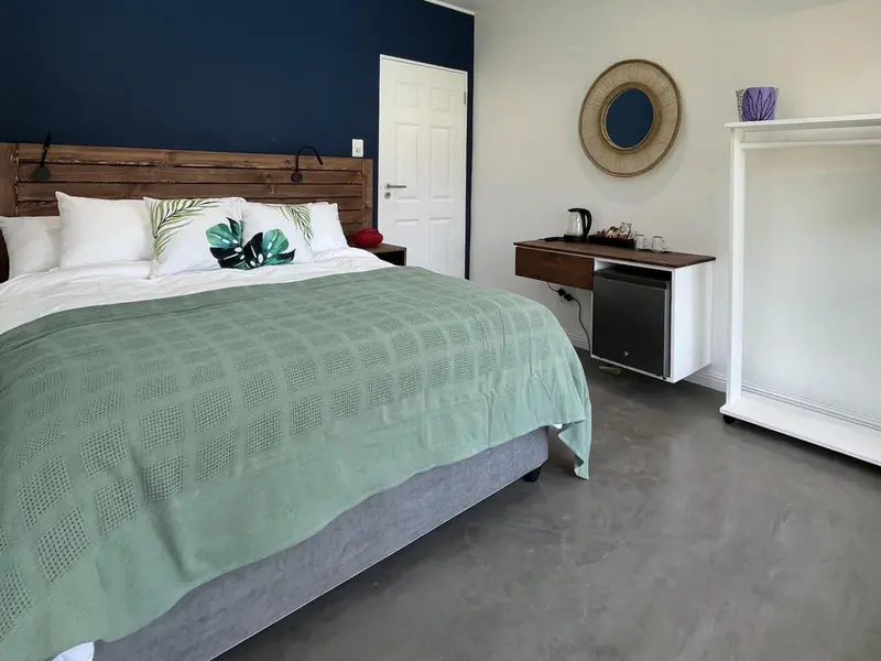 Une chambre lumineuse avec un grand lit recouvert d'une couverture verte et d'oreillers blancs.