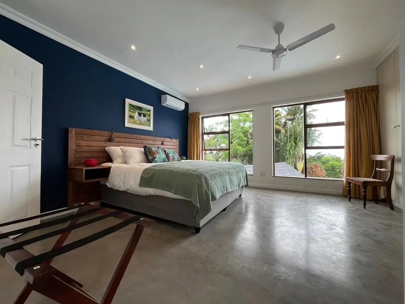Une chambre lumineuse avec un grand lit et une vue sur la végétation.
