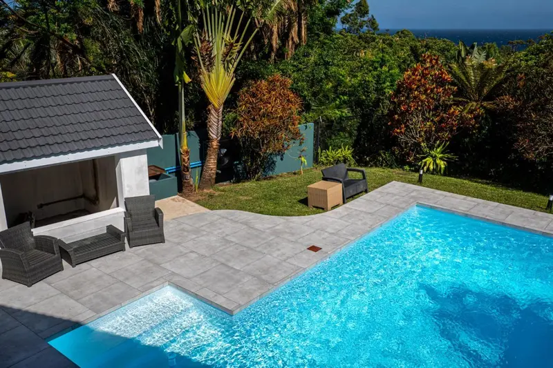 Une piscine rectangulaire avec un espace de détente en extérieur.