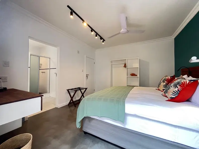 Une chambre lumineuse avec un lit recouvert d'une courtepointe colorée et un accès à un espace ouvert.