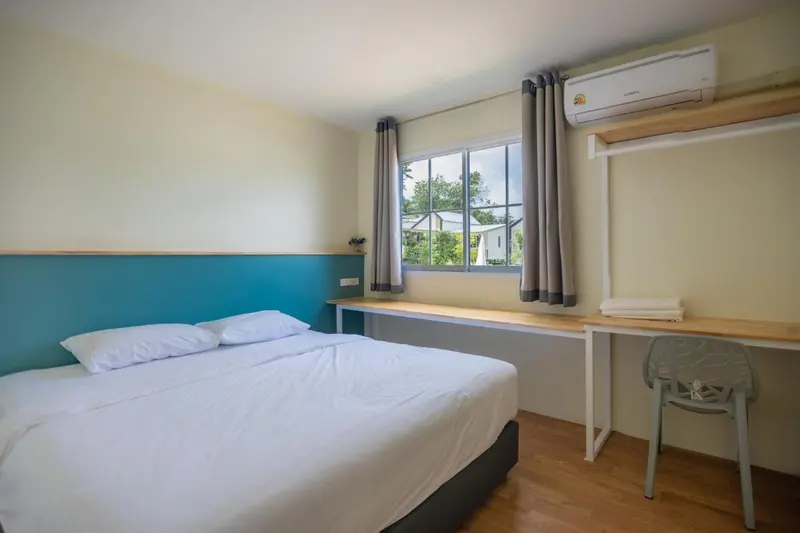 Une chambre lumineuse avec un lit double et un bureau.