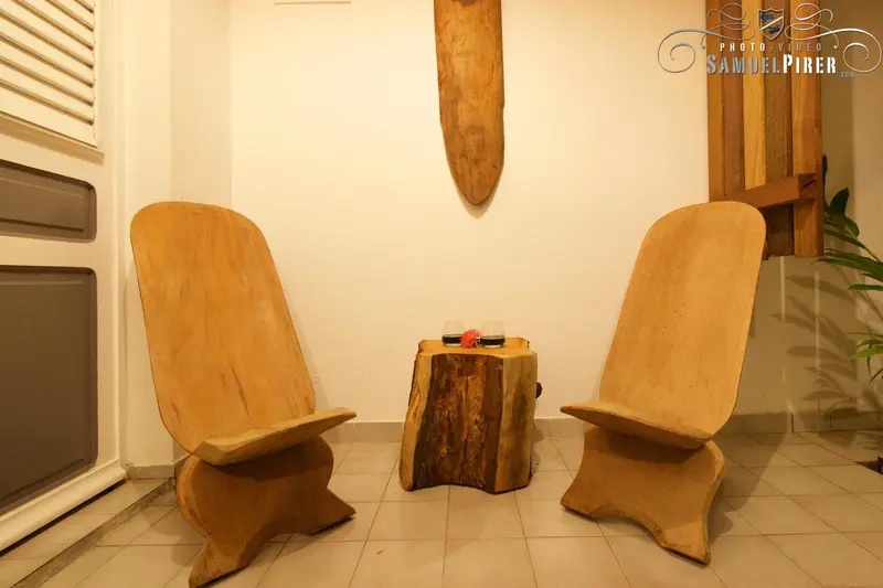 Deux fauteuils en bois sculpté et une table basse dans une pièce lumineuse.