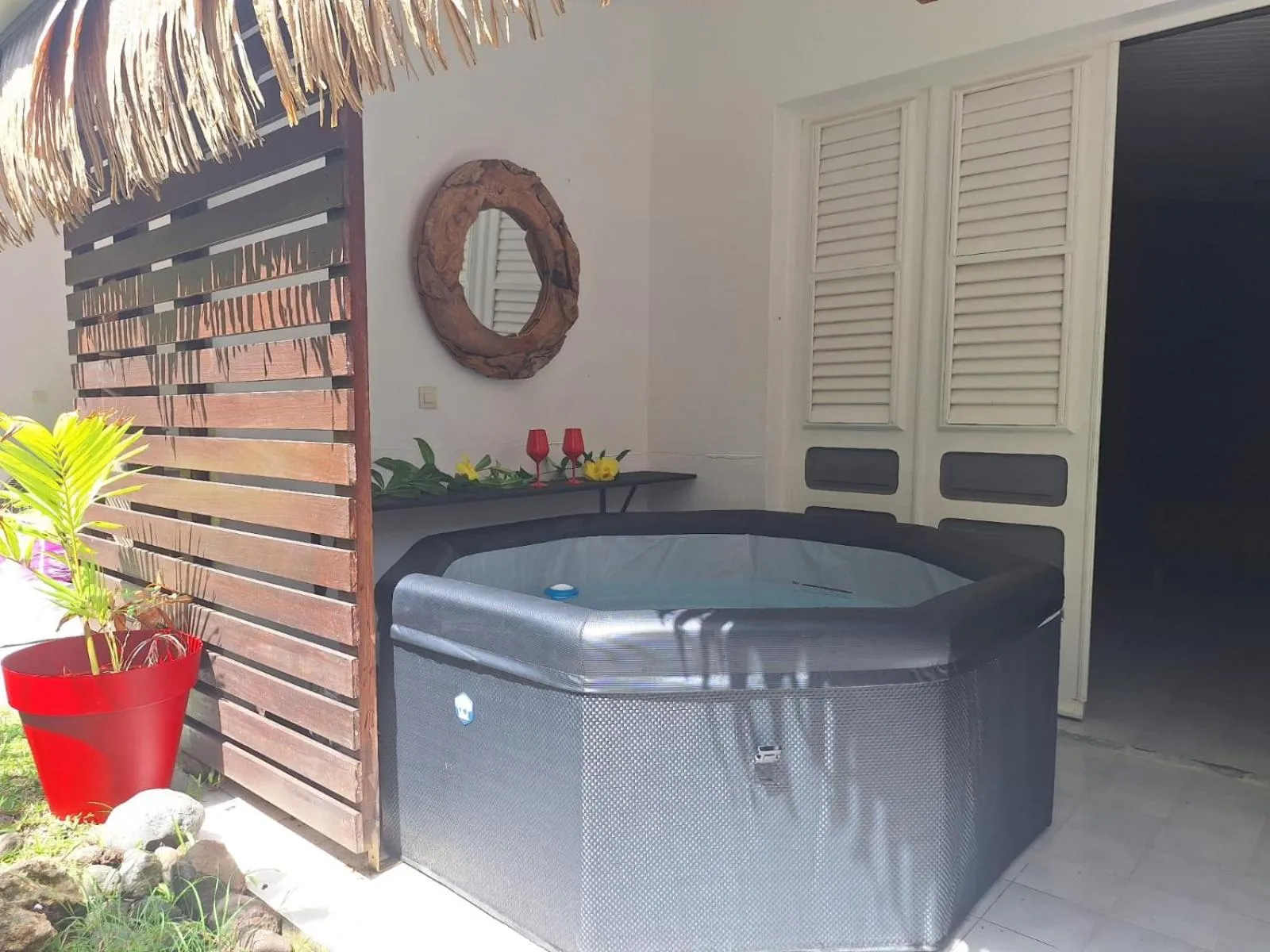 Un jacuzzi extérieur est installé sur une terrasse ombragée.