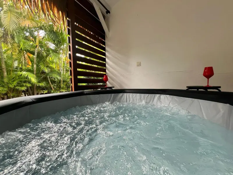 Un jacuzzi extérieur offre un moment de détente face à une végétation luxuriante.