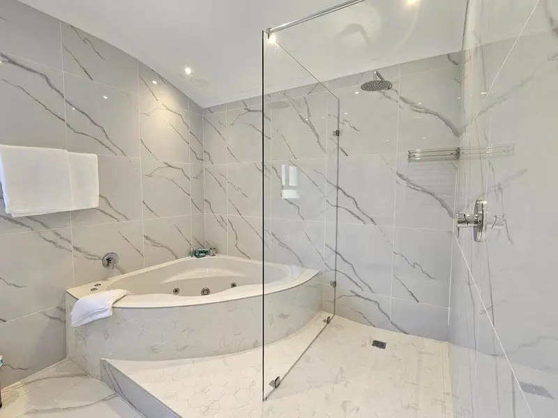 Une salle de bain moderne avec une baignoire d'angle et une douche à l'italienne.