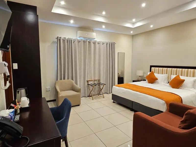 Une chambre d'hôtel lumineuse avec un lit double et un coin salon.