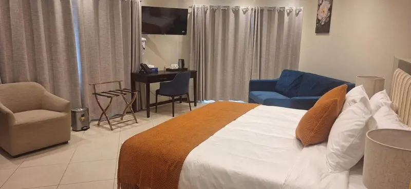 Une chambre lumineuse avec un lit fait, un bureau et un coin salon.