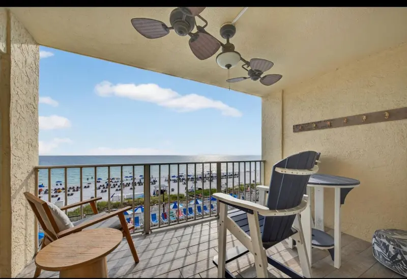 Terrasse avec mobilier d'extérieur donnant sur une plage ensoleillée.