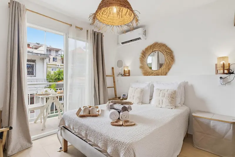 Une chambre lumineuse avec un lit fait et un accès à un balcon.