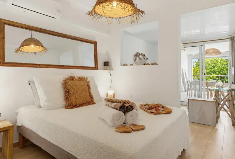 Une chambre lumineuse avec un lit recouvert de coussins et de serviettes.