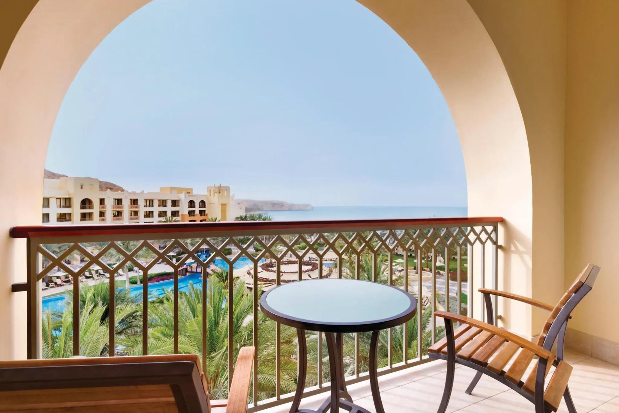 Une terrasse avec une table et des chaises offre une vue sur la mer et une piscine.