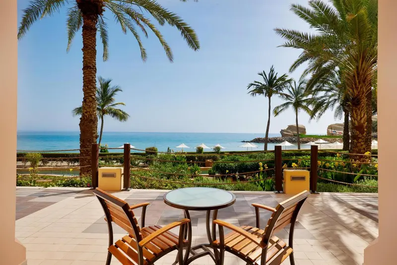 Terrasse avec mobilier en bois donnant sur la mer et la végétation.