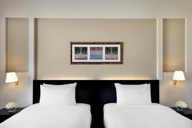 Une chambre avec deux lits simples et une décoration murale.