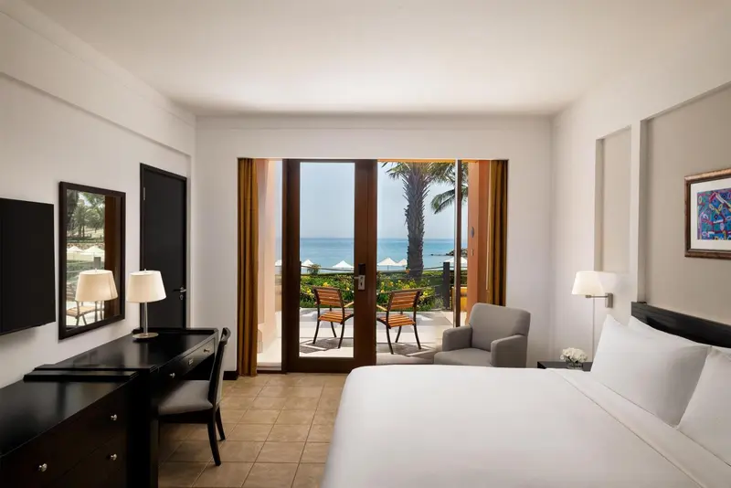 Chambre lumineuse avec un lit et un accès à une terrasse vue sur mer.