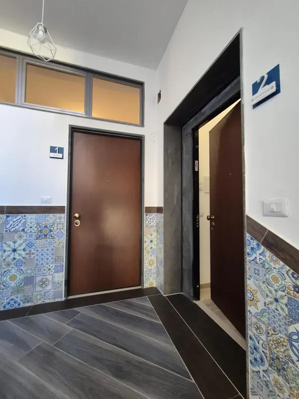 Couloir d'hôtel avec deux portes numérotées et des carreaux décoratifs.