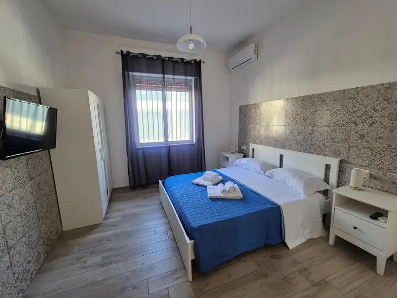 Chambre lumineuse avec un grand lit et une décoration murale texturée.