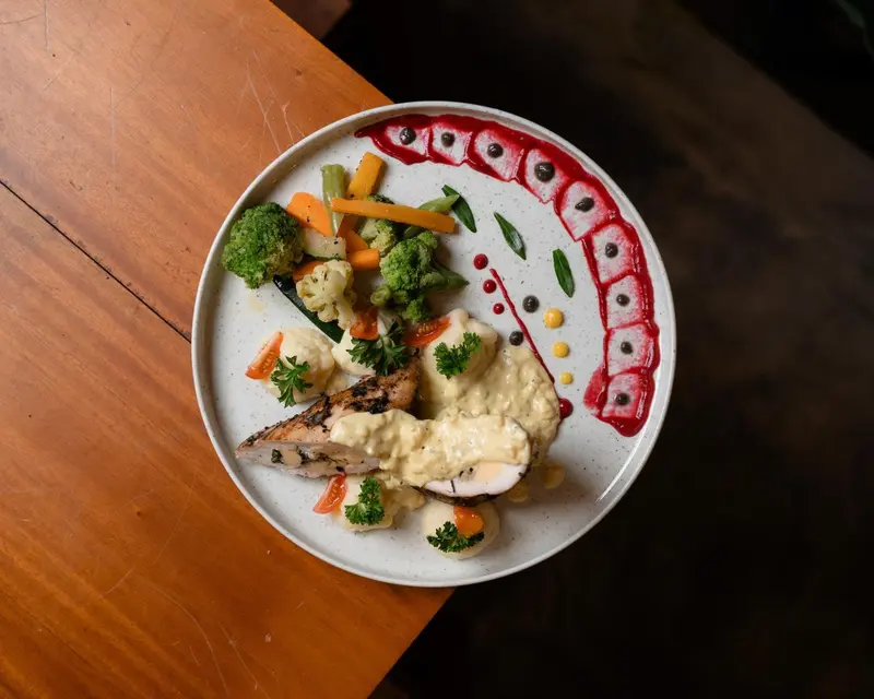 Assiette de poisson avec légumes et sauce décorée.