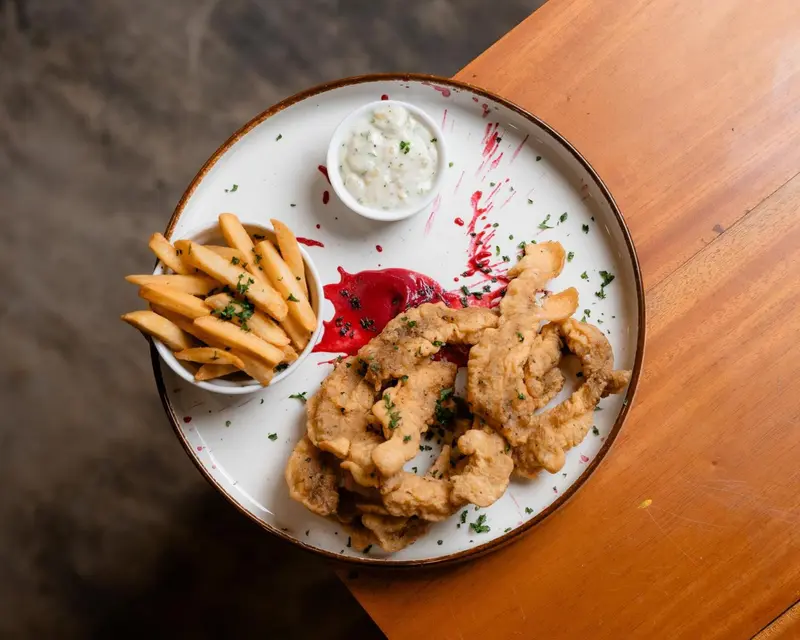 Assiette de frites, de calamars frits et de sauces.