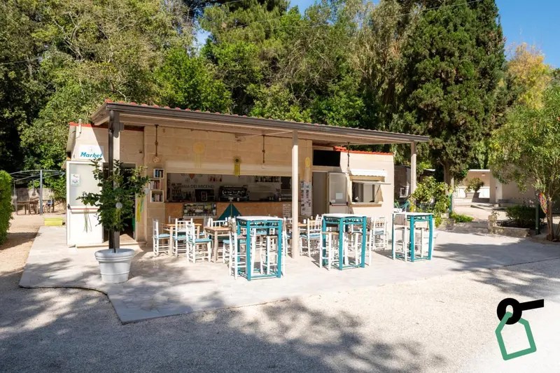 Un comptoir de vente extérieur avec des tables et des chaises sur un sol gravillonné.