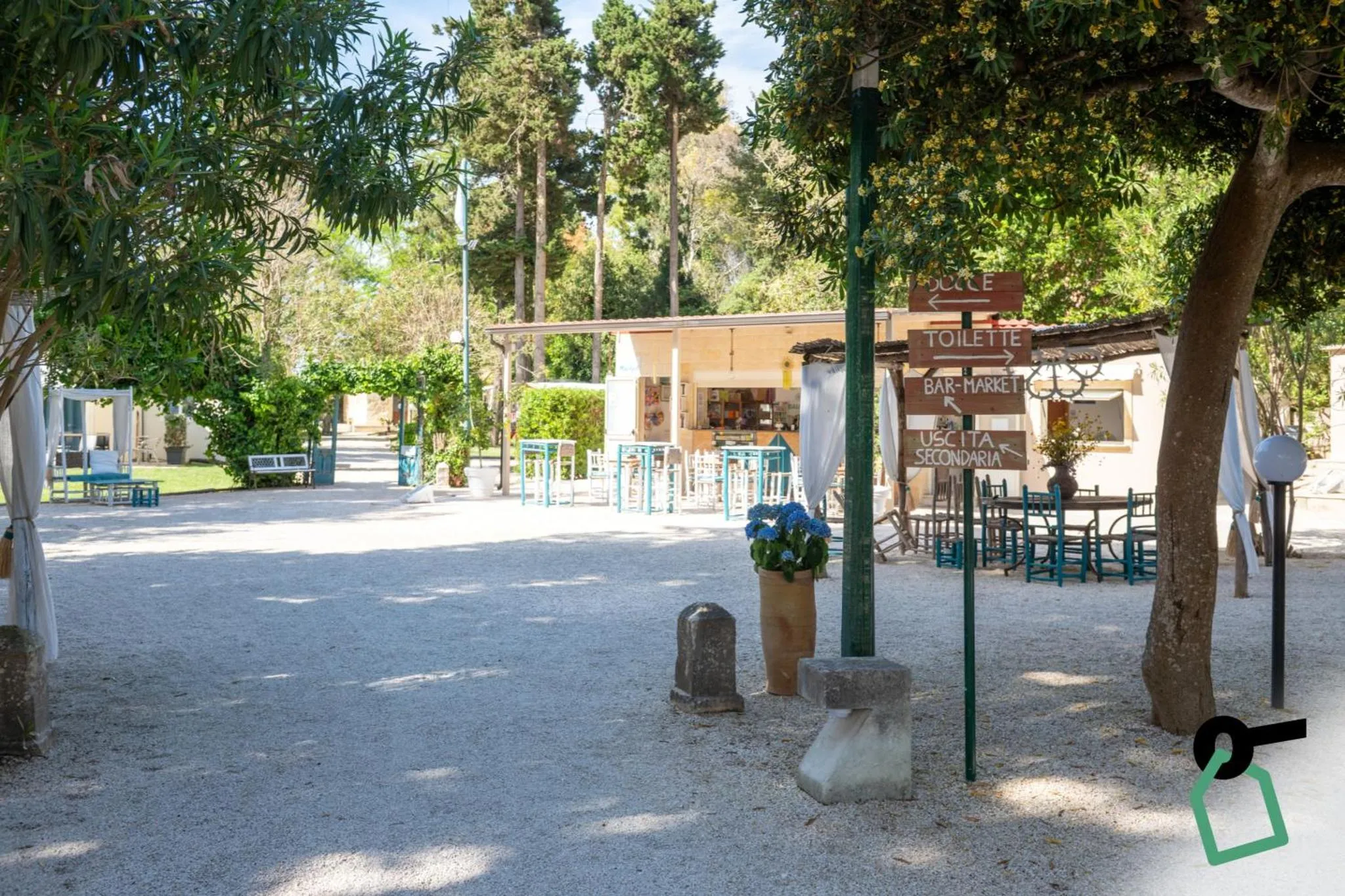 Terrasse ombragée avec tables et chaises, devant un bar-market.