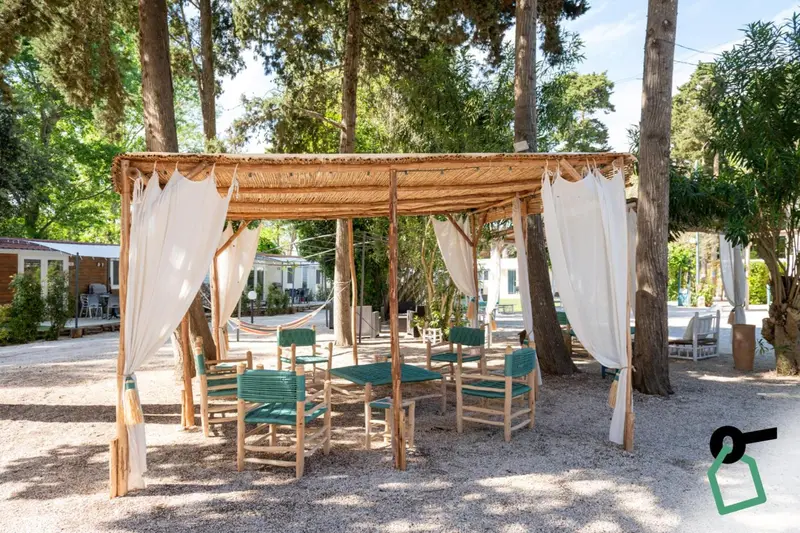 Espace de restauration extérieur ombragé avec tables et chaises.