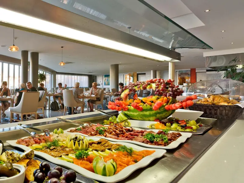 Un buffet propose une grande variété de fruits, de charcuteries et de viennoiseries.