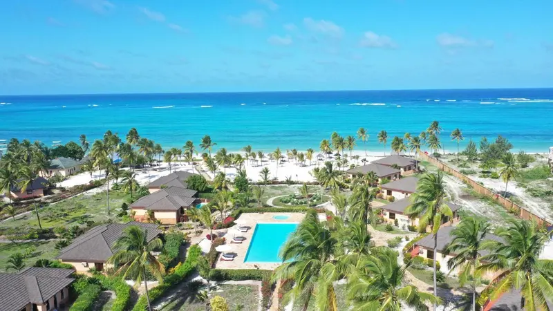 Vue aérienne d'un complexe hôtelier bordant une plage de sable blanc et une mer turquoise.