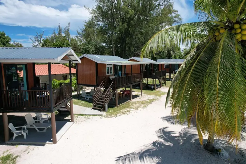 Cabanes en bois sur pilotis alignées le long d'un chemin de sable.