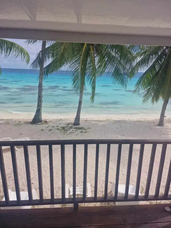 Vue sur une plage de sable blanc bordée de palmiers et d'une mer turquoise.
