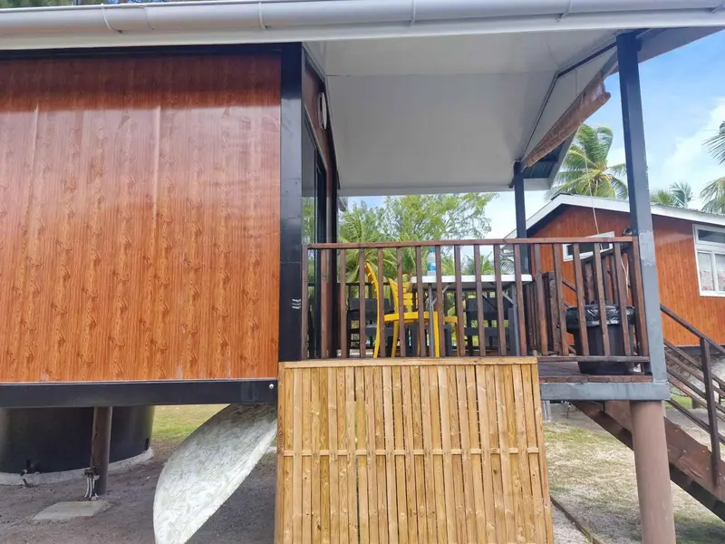 Logement sur pilotis avec terrasse en bois et garde-corps.