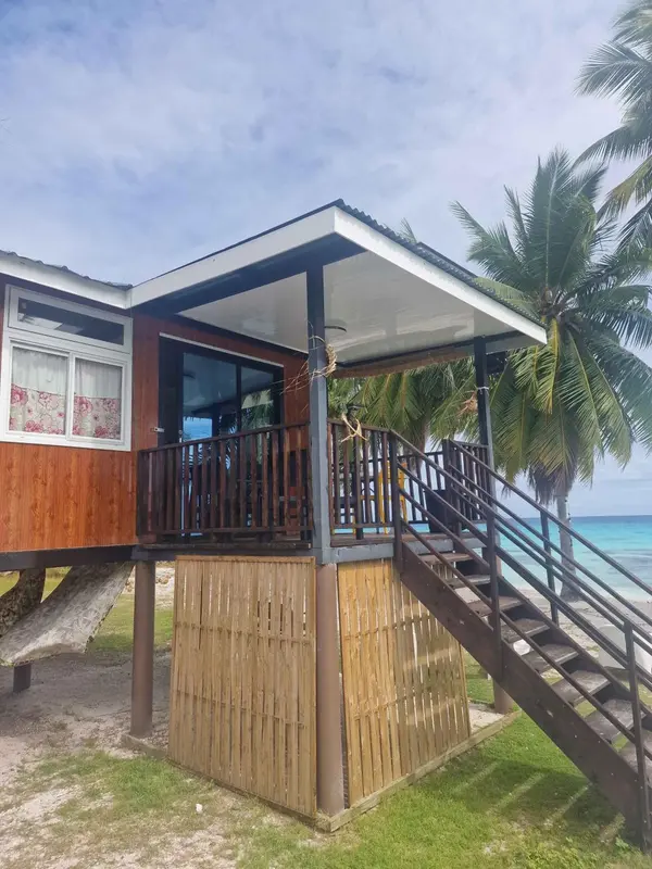 Une habitation sur pilotis avec une terrasse en bois et un escalier d'accès.
