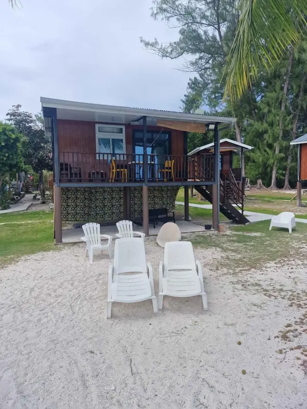 Logement sur pilotis avec terrasse donnant sur une plage de sable blanc.