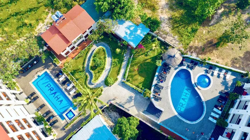 Vue aérienne d'un complexe hôtelier avec piscine sinueuse et végétation tropicale.