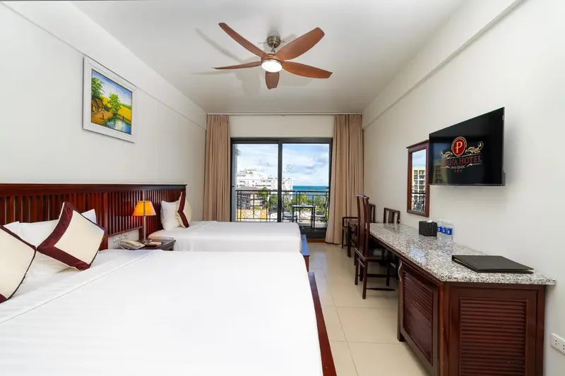 Chambre lumineuse avec deux lits simples et vue sur la mer.