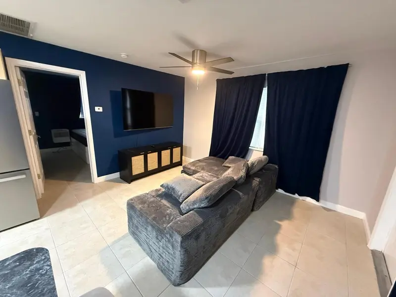 Un salon moderne avec un grand canapé et un téléviseur mural.