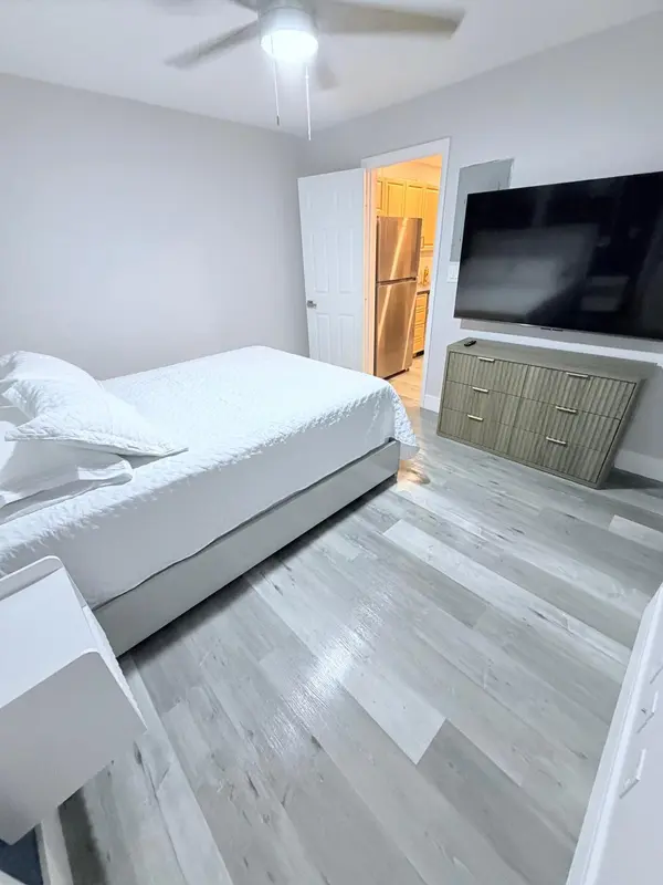 Une chambre lumineuse avec un lit et un meuble télévision.