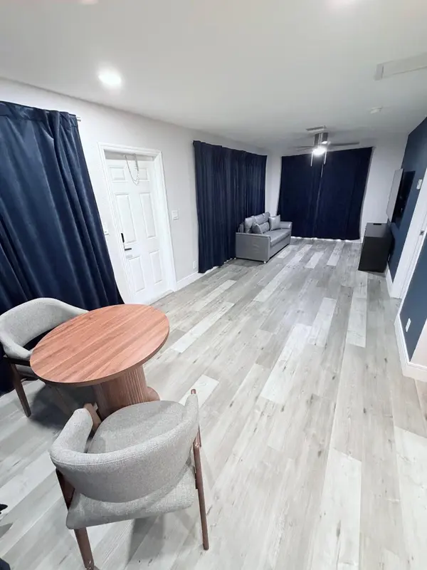 Une table ronde en bois est entourée de deux chaises dans une pièce lumineuse.