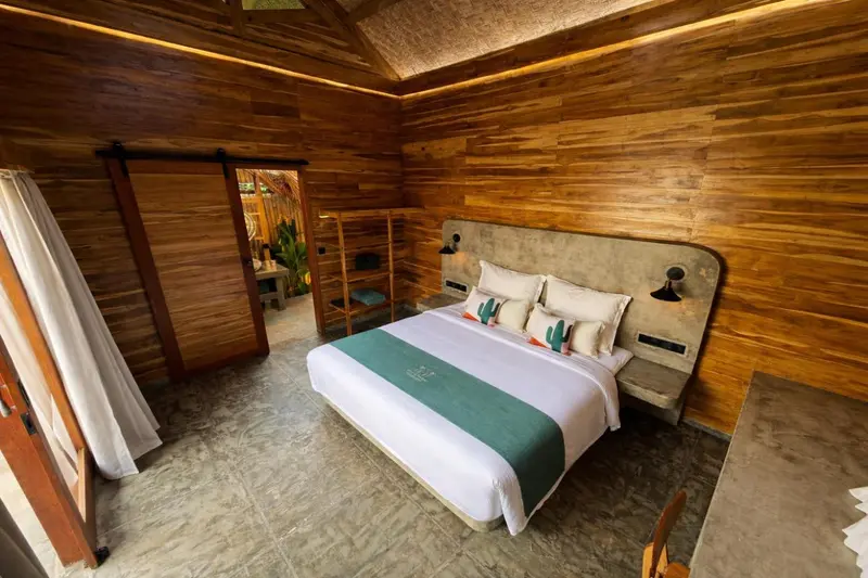 Une chambre lumineuse avec un grand lit recouvert d'une courtepointe verte.