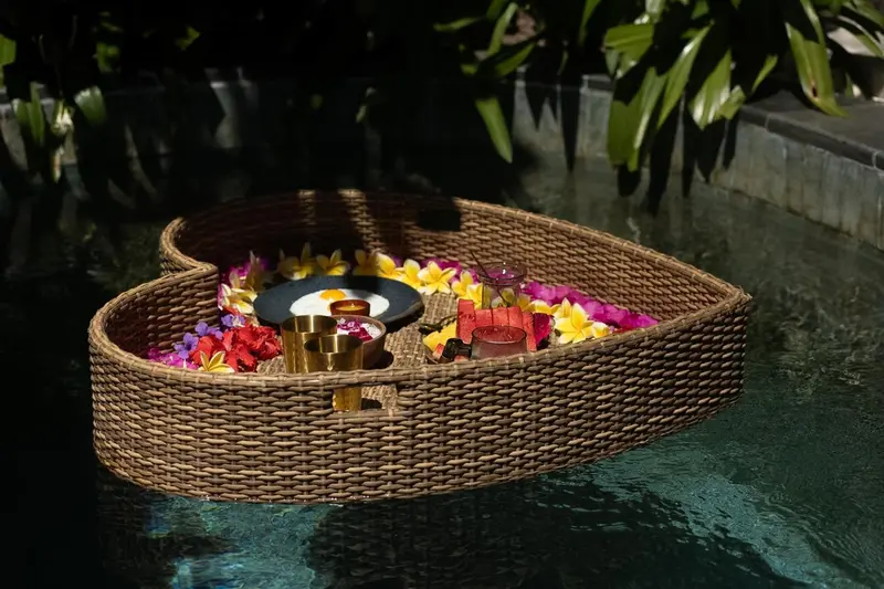 Un petit-déjeuner flottant est présenté dans une barque en osier décorée de fleurs.