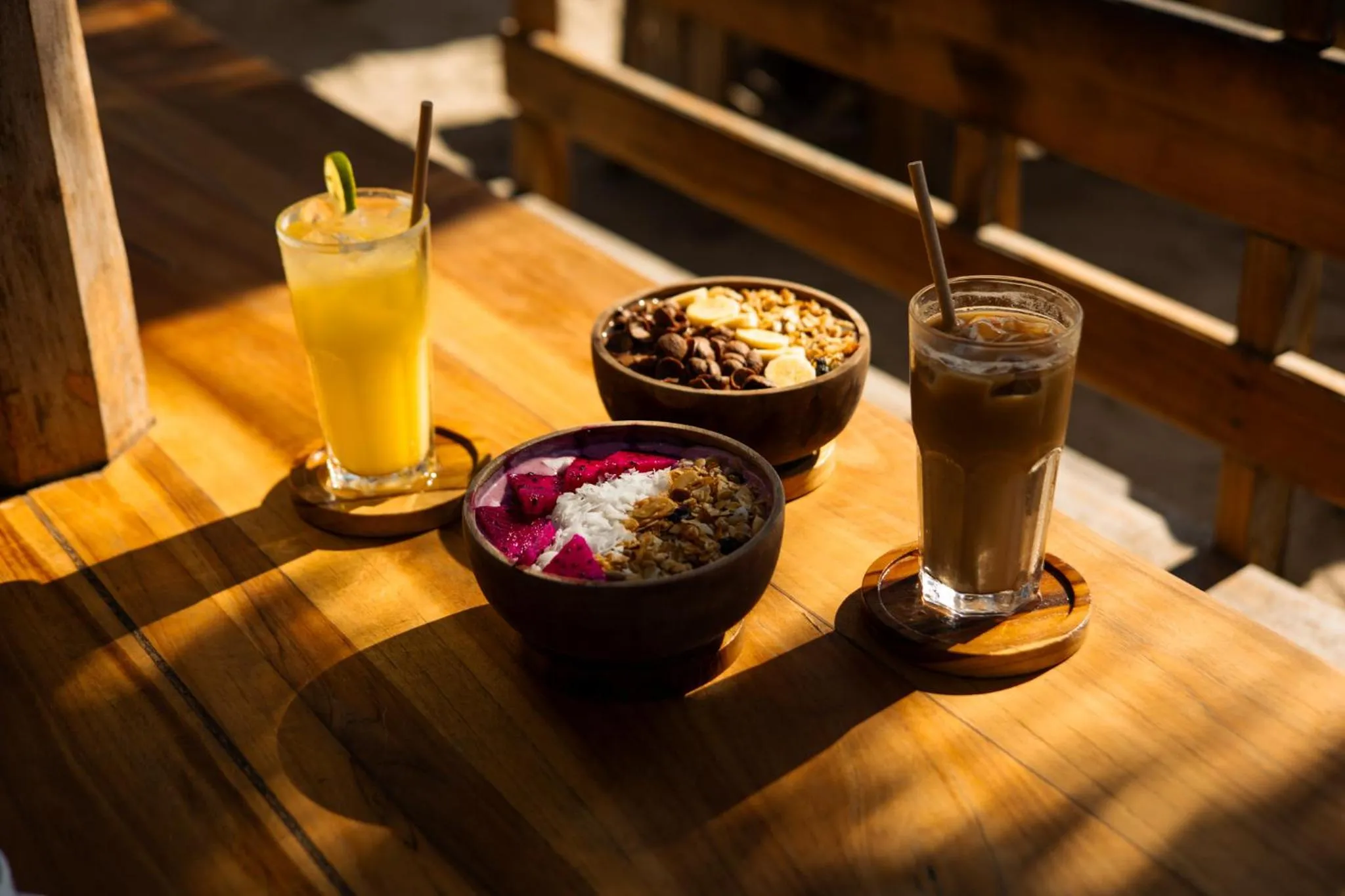 Des boissons et des bols de fruits frais sont présentés sur une table en bois.